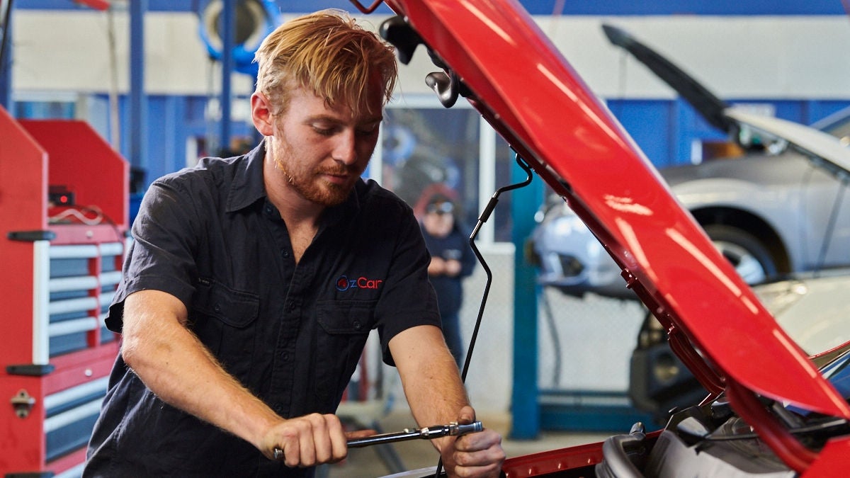 Self-employed tradie working under a car bonnet